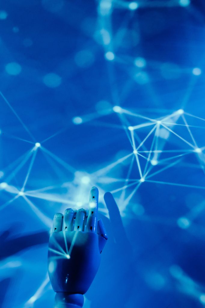 Cette image représente une main robotisée posée sur un fond bleu constellée de points blancs.